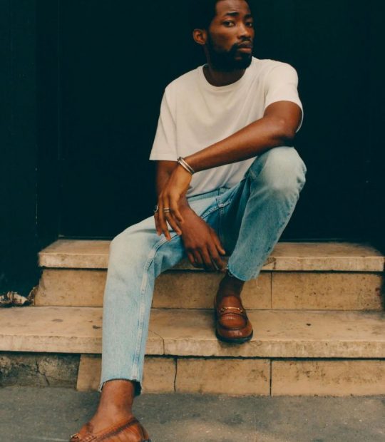 Black male model wearing white tshirt and denim pants