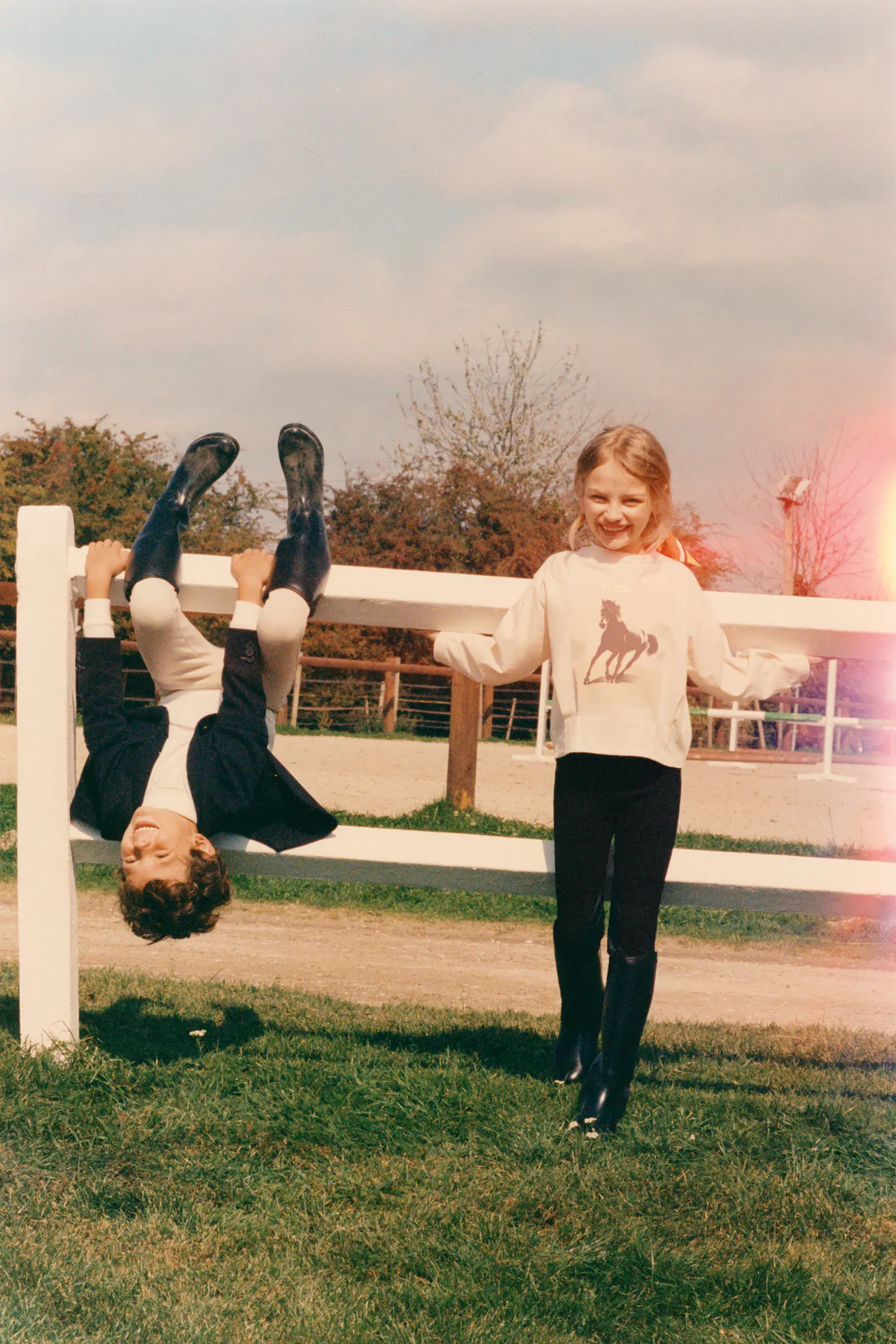 Two children playing around a horse stable